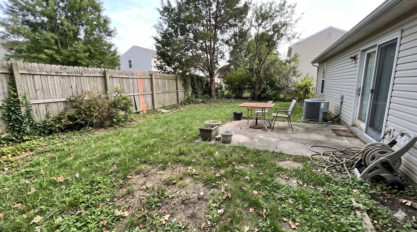 Another angle: cracked patio, old metal table and chairs, empty planters and a hose reel by the back door